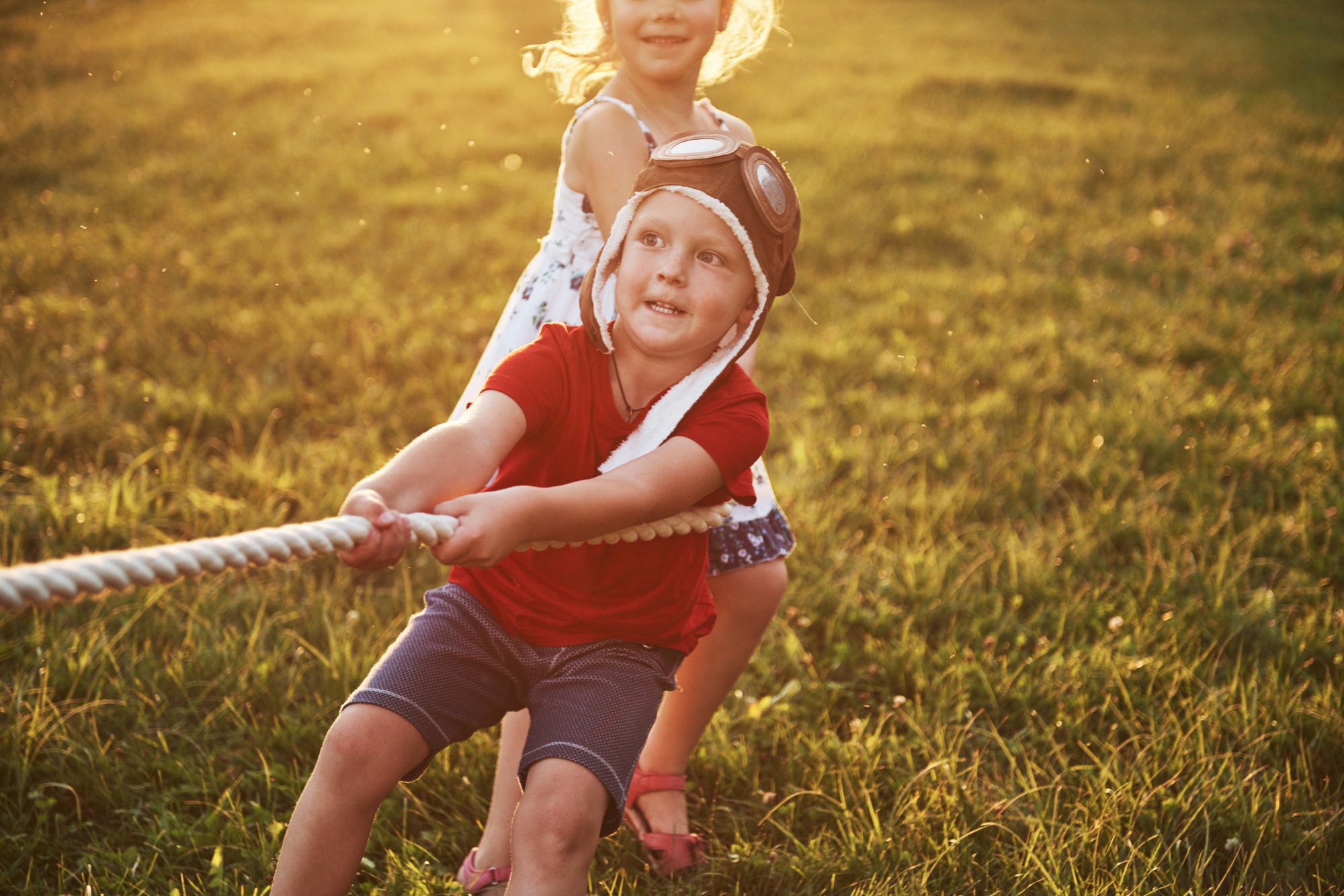 Boy and girl pulling a rope and playing tug of war at the park
