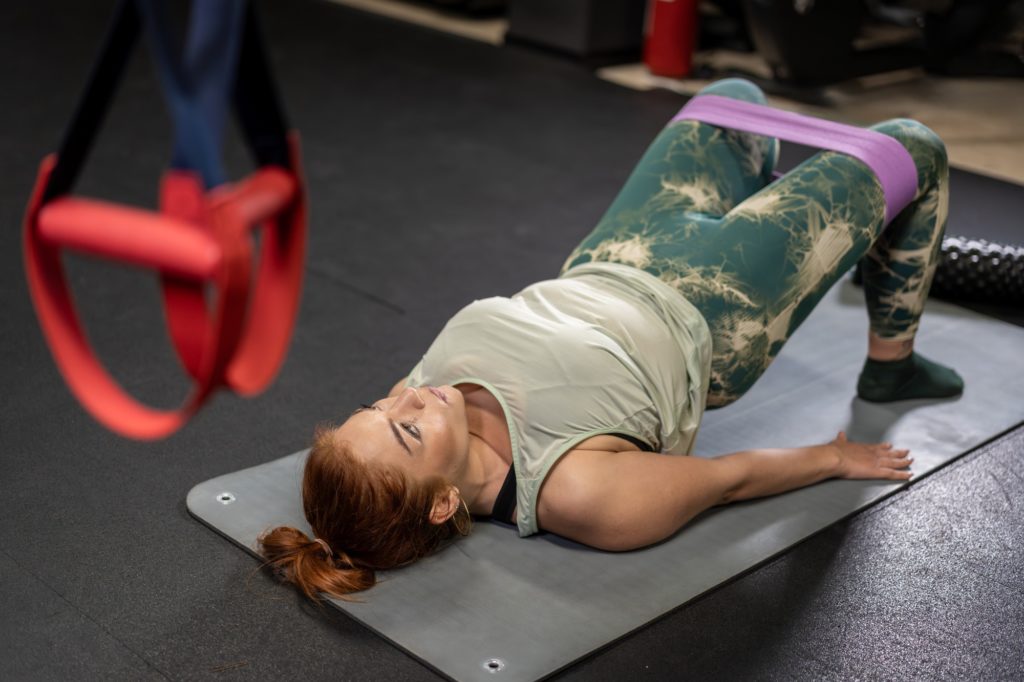Woman performing glute bridge exercise with resistance band in gym