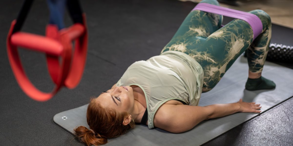 Woman performing glute bridge exercise with resistance band in gym