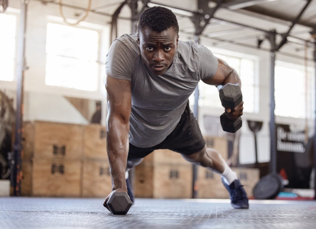 Fullbody young african american athlete lifting dumbbell during tricep curl workout in gym. Strong,